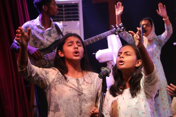 Two girls singing with their hands raised