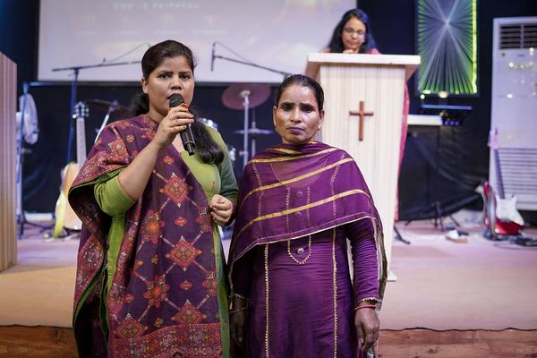 Two women sharing a testimony at the front